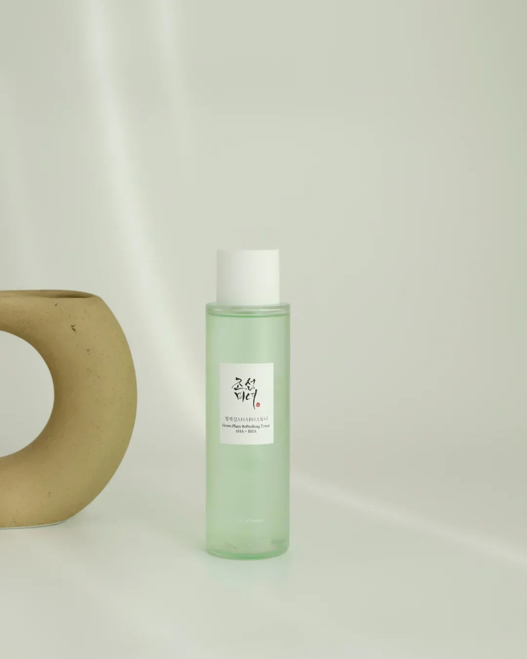 Green Plum Refreshing Toner AHA BHA in translucent green bottle with white cap on white surface