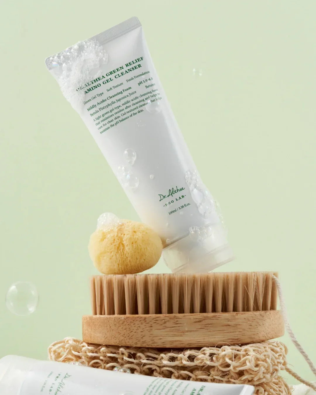 Dr. Althea Green Relief Amino Gel Cleanser with foam, sponge, wooden brush on beige cloth