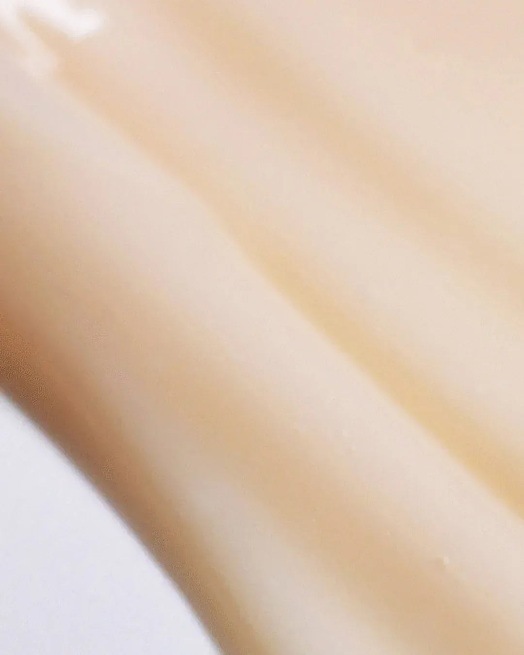 Smooth beige cream or lotion texture with soft streaks, close-up detail of skincare product