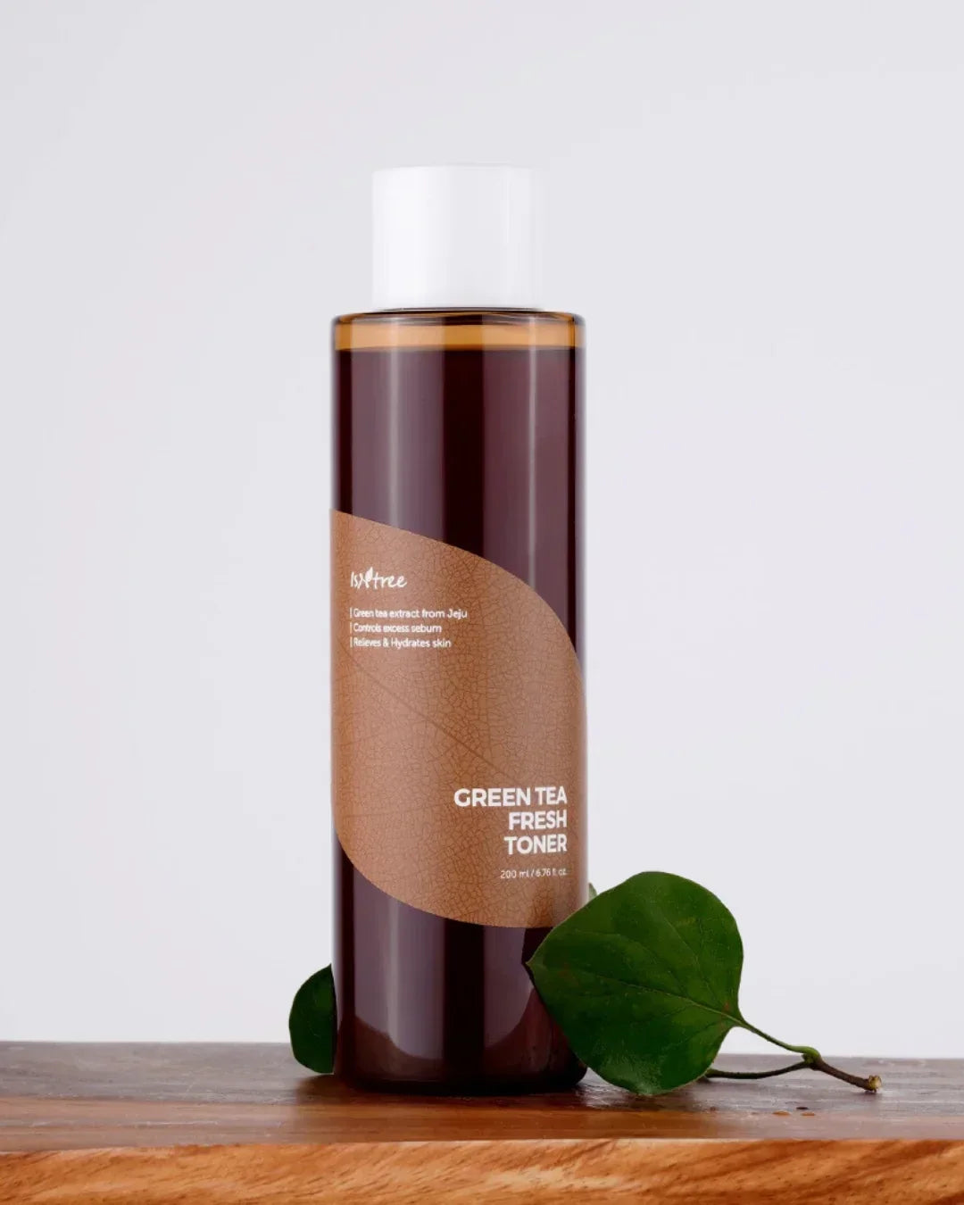 Isntree Green Tea Fresh Toner 200ml bottle with leaf on wooden surface against light background