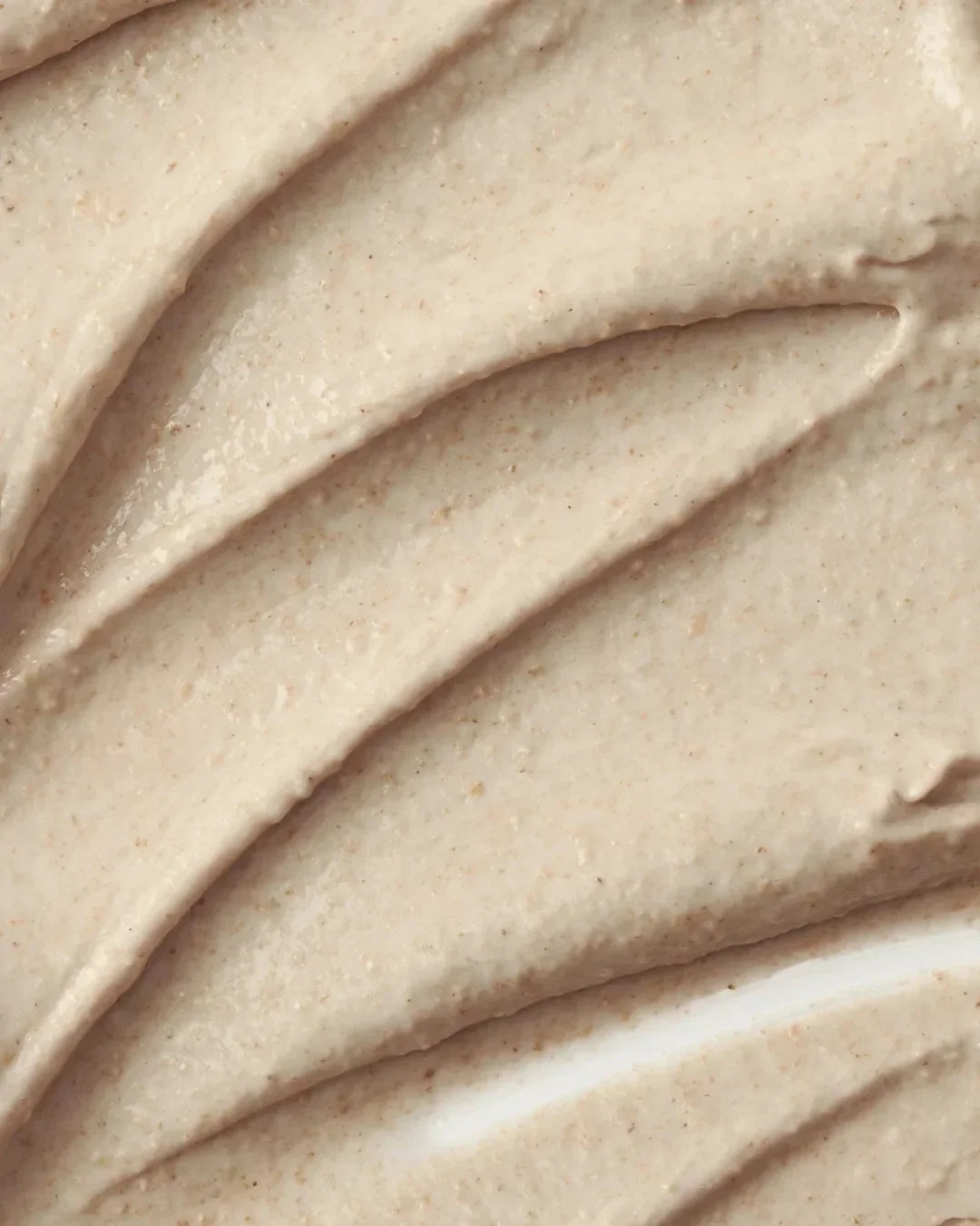 Close-up of creamy ground rice and honey glow mask texture with smooth, grainy beige swirls