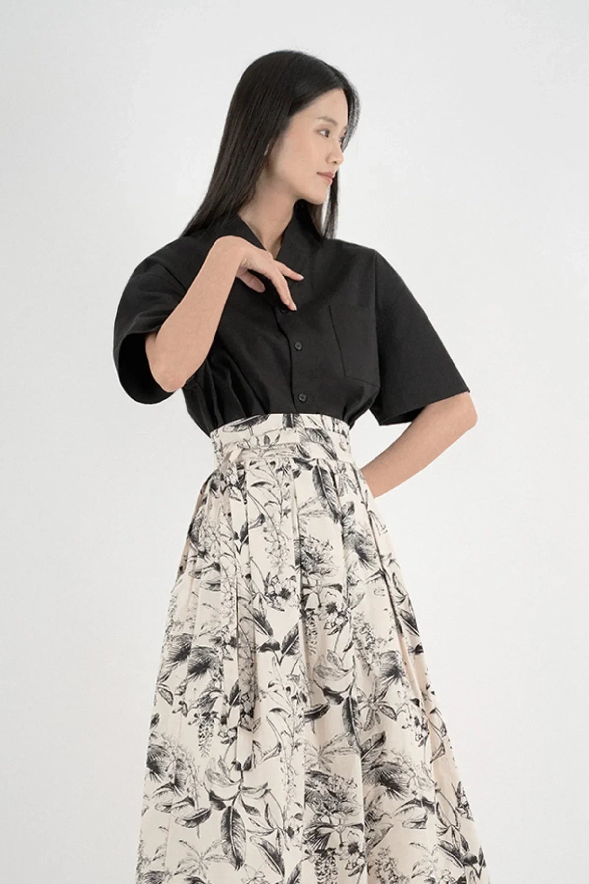 Woman wearing black short-sleeved shirt and high-waisted floral print skirt
