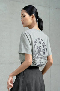 Woman wearing gray Seoul-themed T-shirt with tiger graphic and text, paired with dark pleated skirt