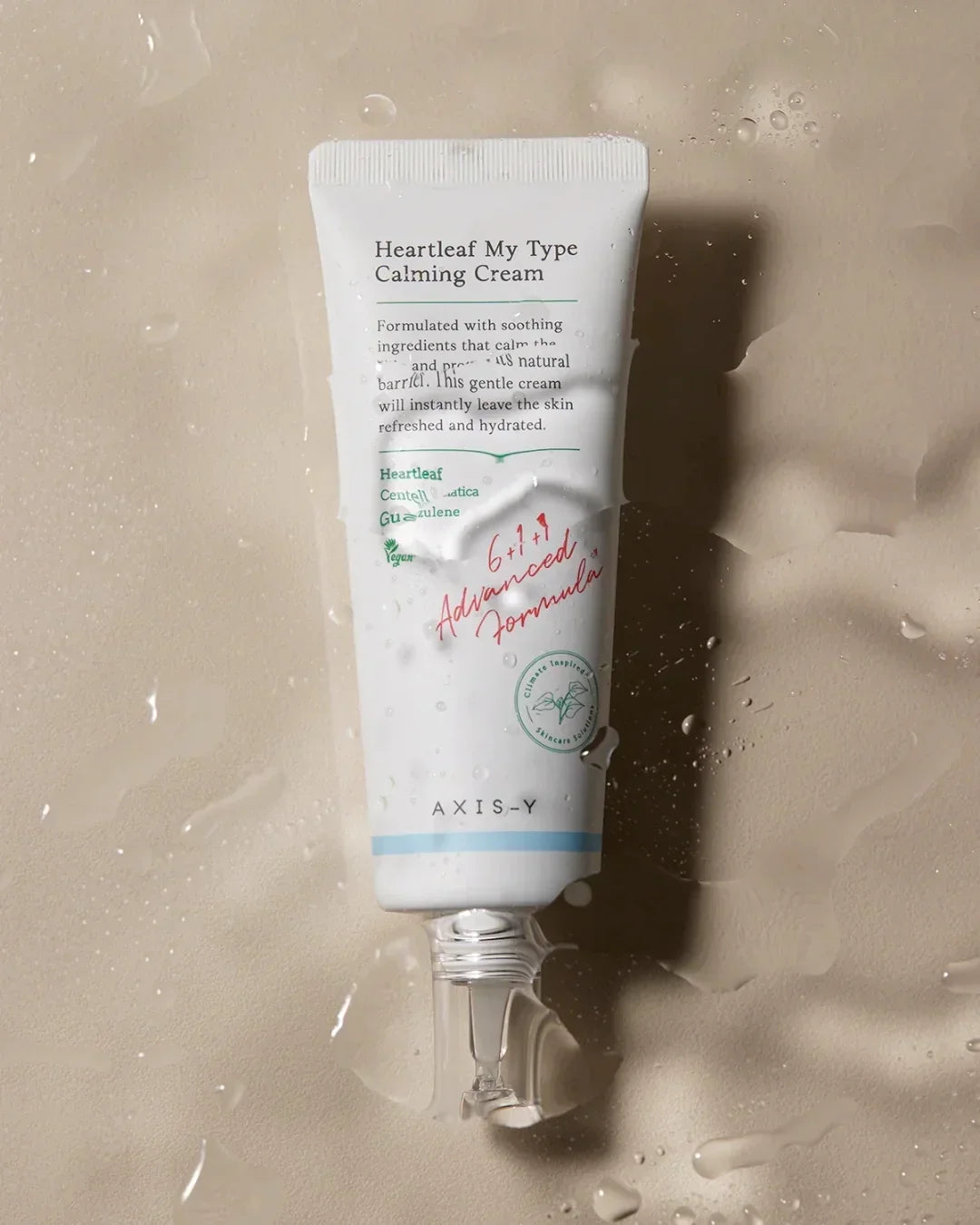 Tube of Axis-Y Heartleaf My Type Calming Cream with water drops on beige surface