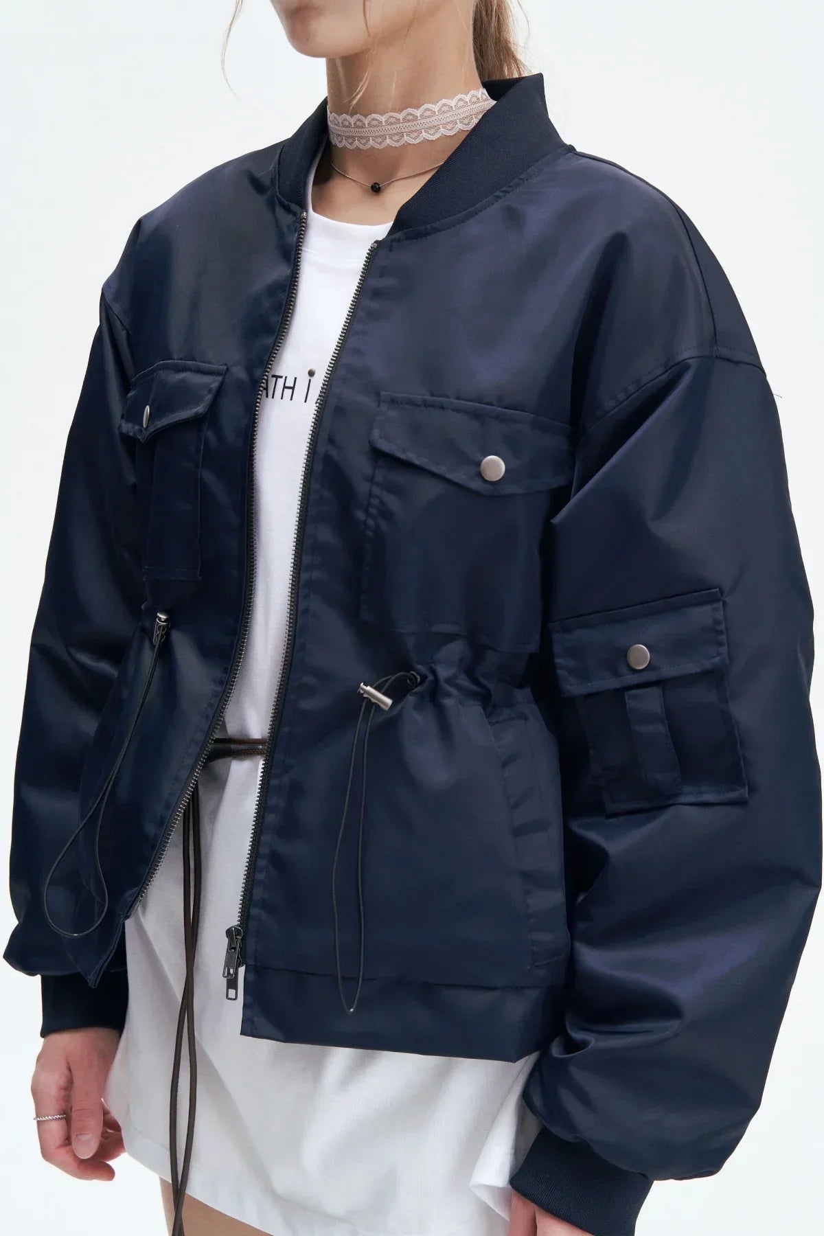 Close-up of navy heavy nylon bomber jacket with front pockets and drawstring on a woman