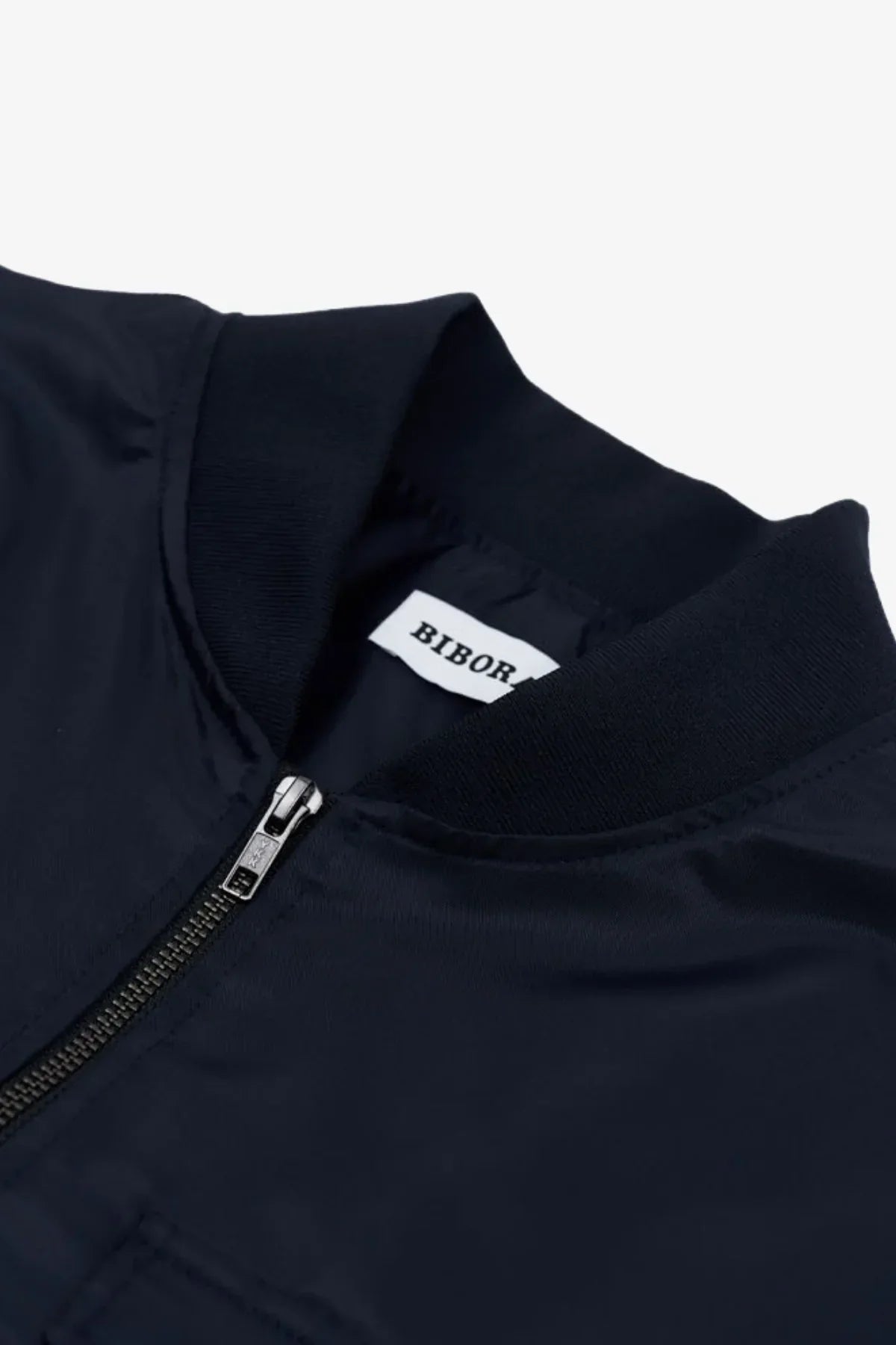 Close-up of navy blue heavy nylon bomber jacket collar with silver zipper and BIBOR label