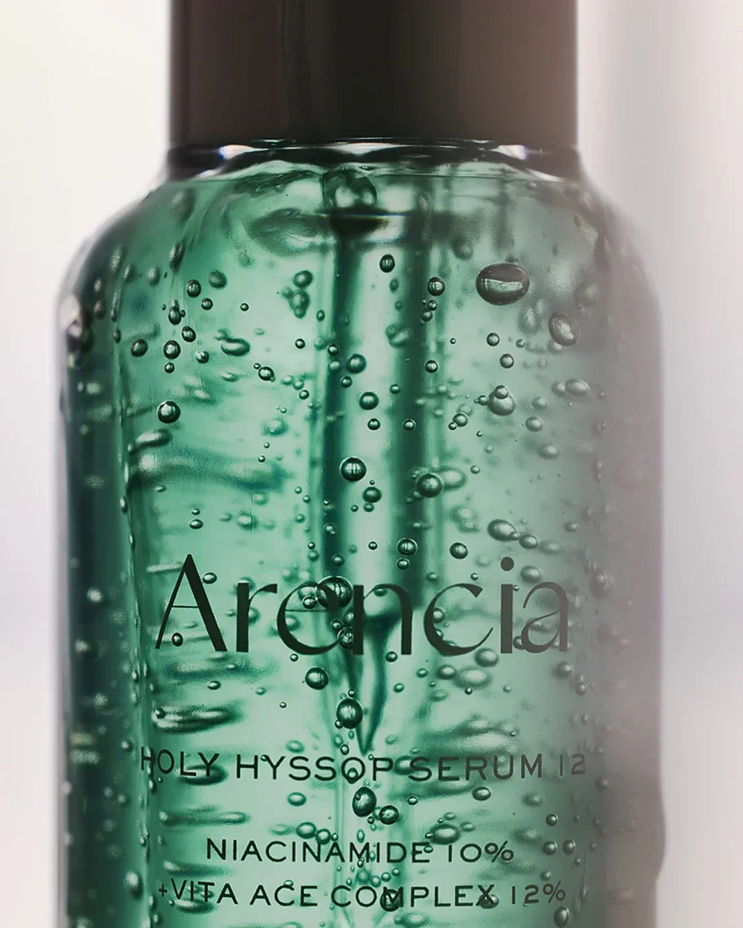 Arencia Holy Hyssop Serum bottle with green gel and visible air bubbles, studio close-up