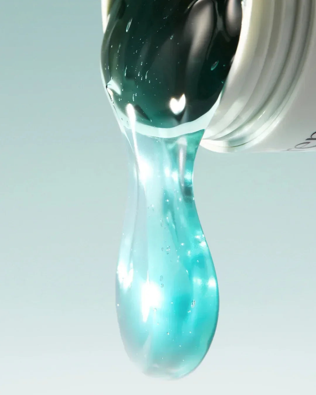 Close-up of blue glossy serum pouring from white cosmetic jar on light background
