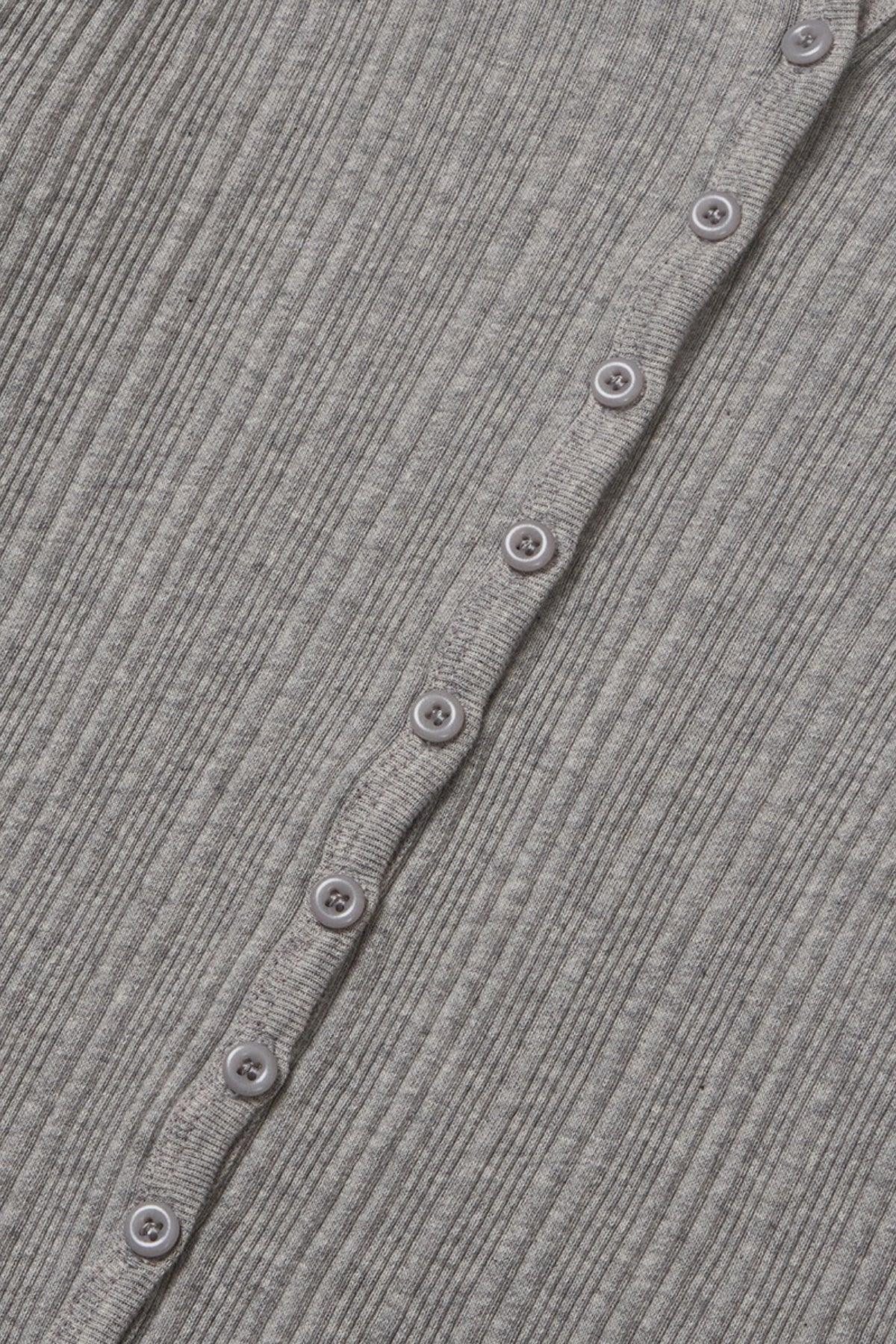 Close-up of gray ribbed knit fabric with gray buttons on a hooded cardigan