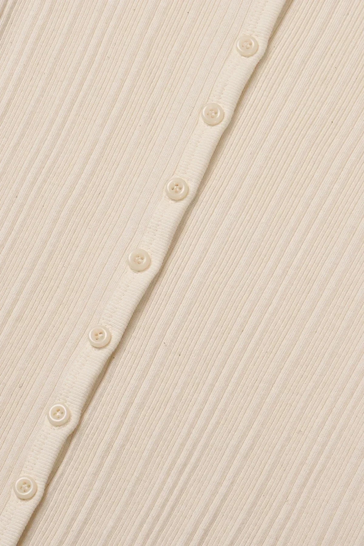 Close-up of natural cream ribbed cardigan with small buttons in linen texture