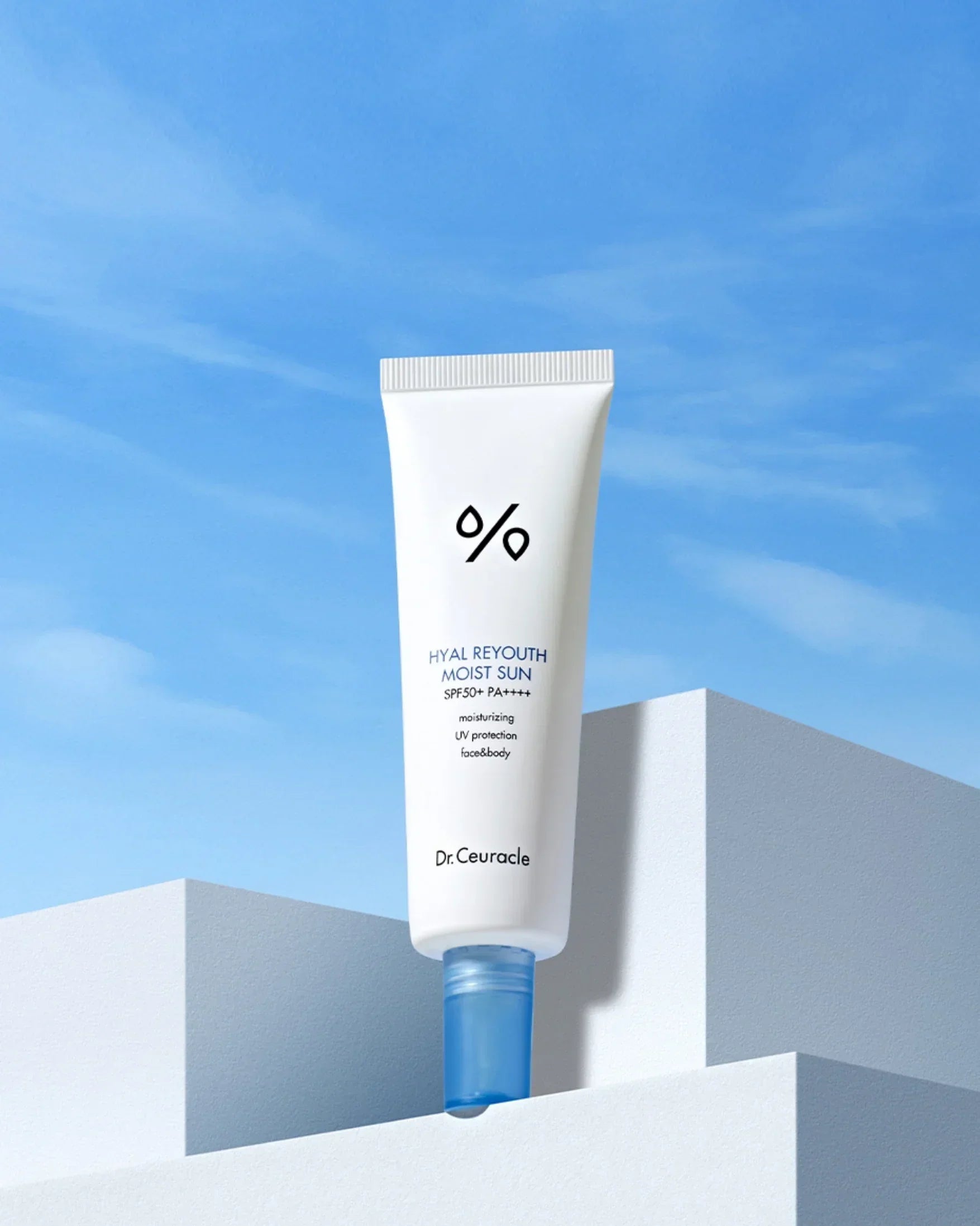 Dr. Ceuracle Hyal Reyouth Moist Sun SPF50+ PA++++ sunscreen tube on white geometric pedestal under blue sky