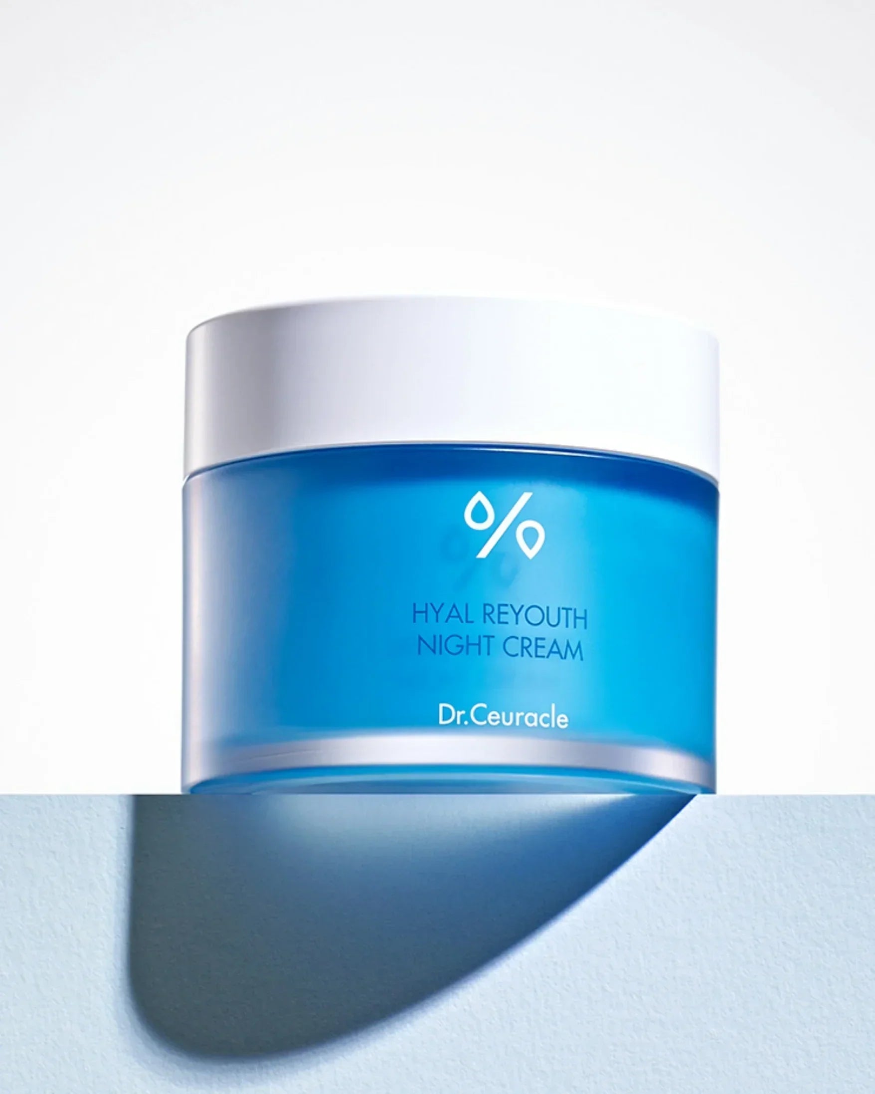 Blue jar of Dr.Ceuracle Hyal Reyouth Night Cream with white lid on light surface casting shadow