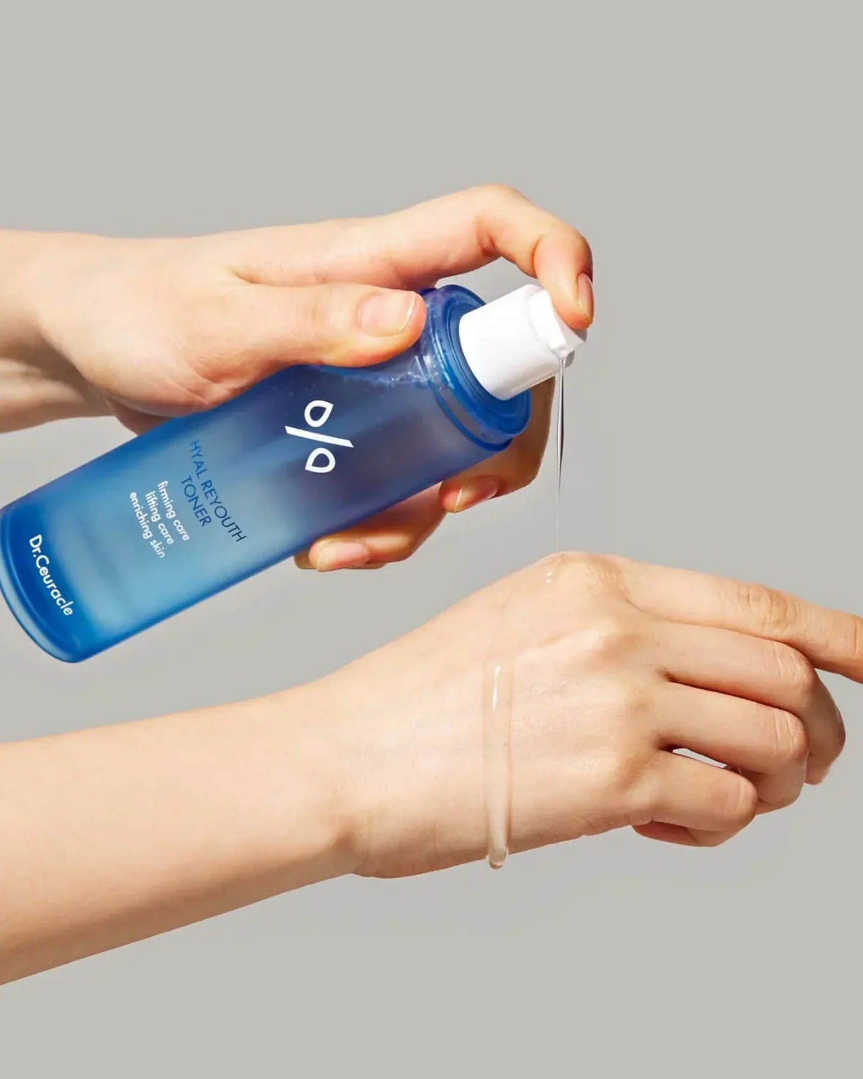 Hand pouring Dr. Ceuracle Hyal Reyouth Toner from blue bottle onto back of another hand