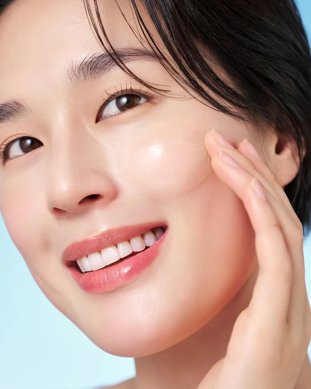Close-up of a woman applying PURITO SEOUL Hydro Wave Deep Sea Serum to her glowing skin.