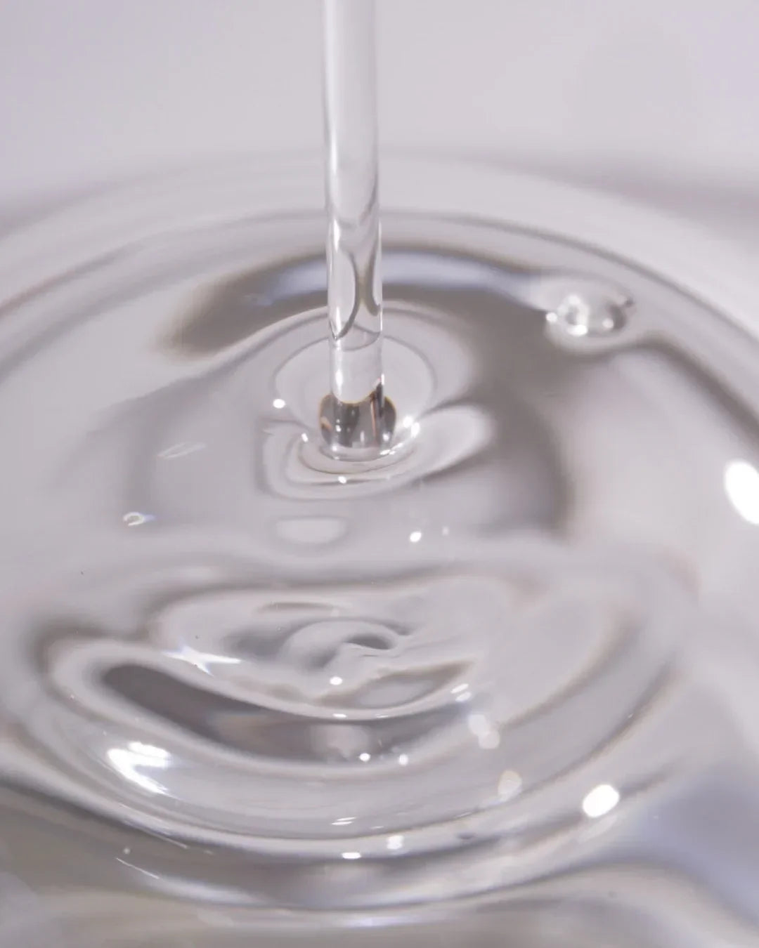 Close-up of clear serum dropper releasing transparent niacinamide serum texture
