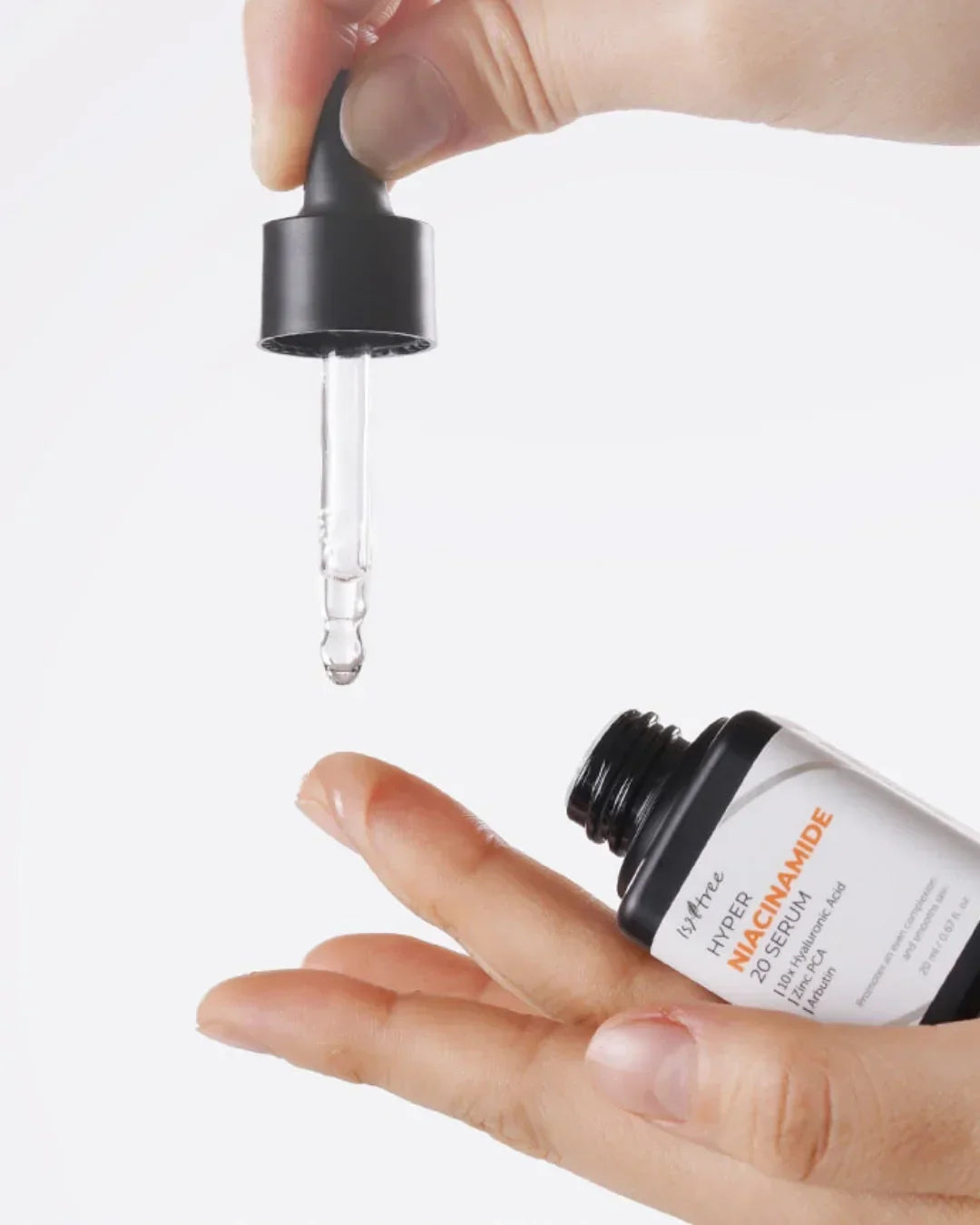 Hand holding dropper and bottle of hyper niacinamide 20 serum with clear liquid drop on finger