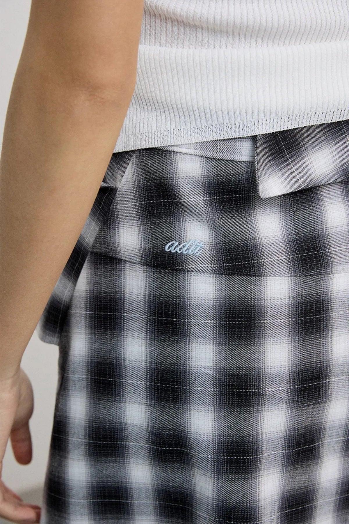 Close-up of a black and white checkered skirt with embroidered logo worn with a white ribbed top