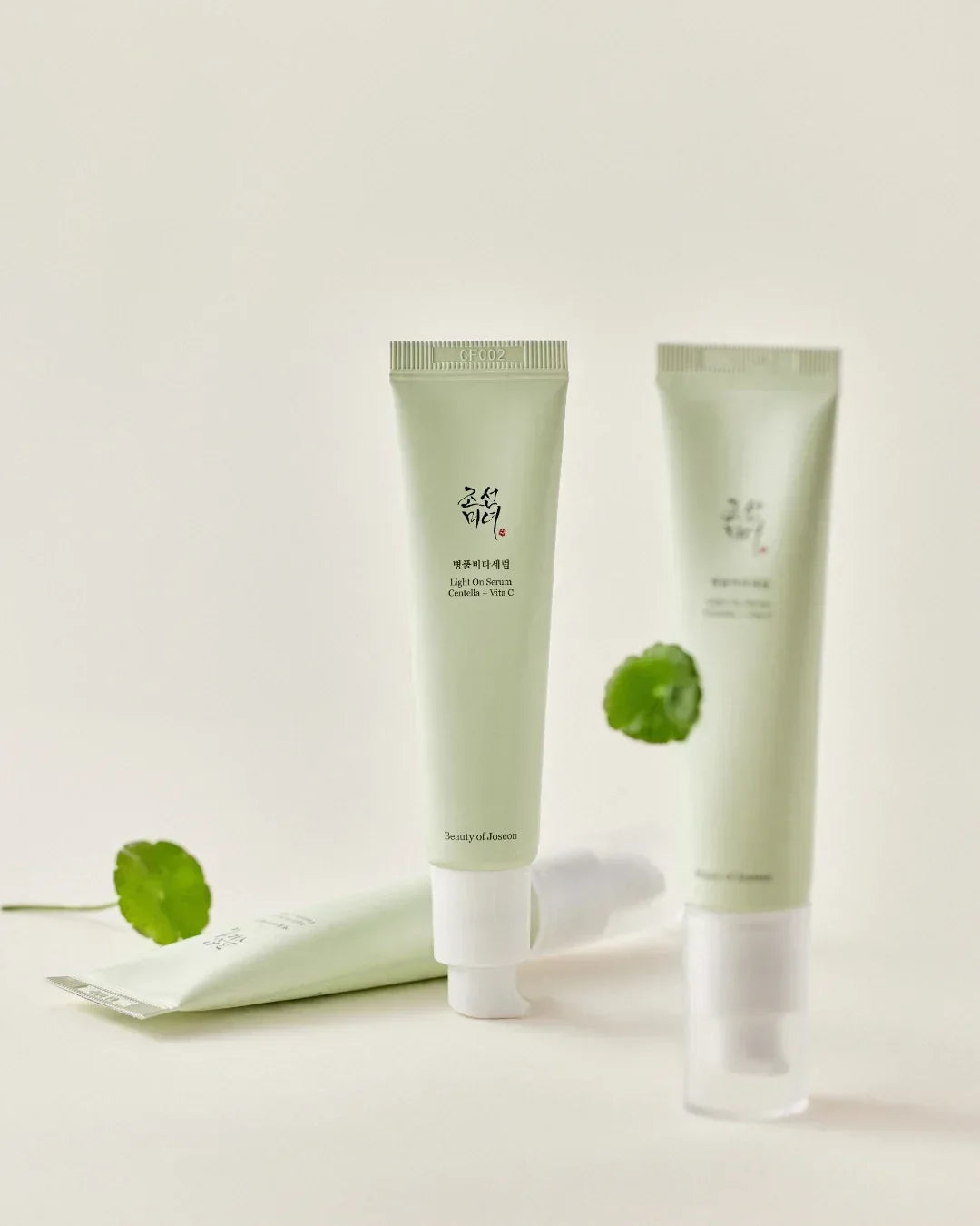 Light On Serum Centella + Vita C 30ml tubes with green leaves on neutral background