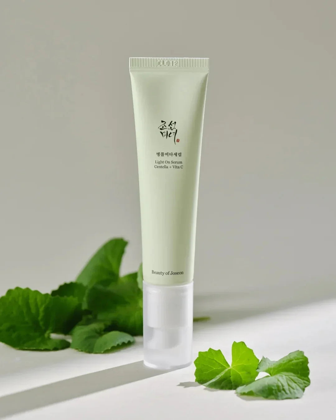 Beauty of Joseon Light On Serum tube with Centella and Vita C beside green centella leaves on light background