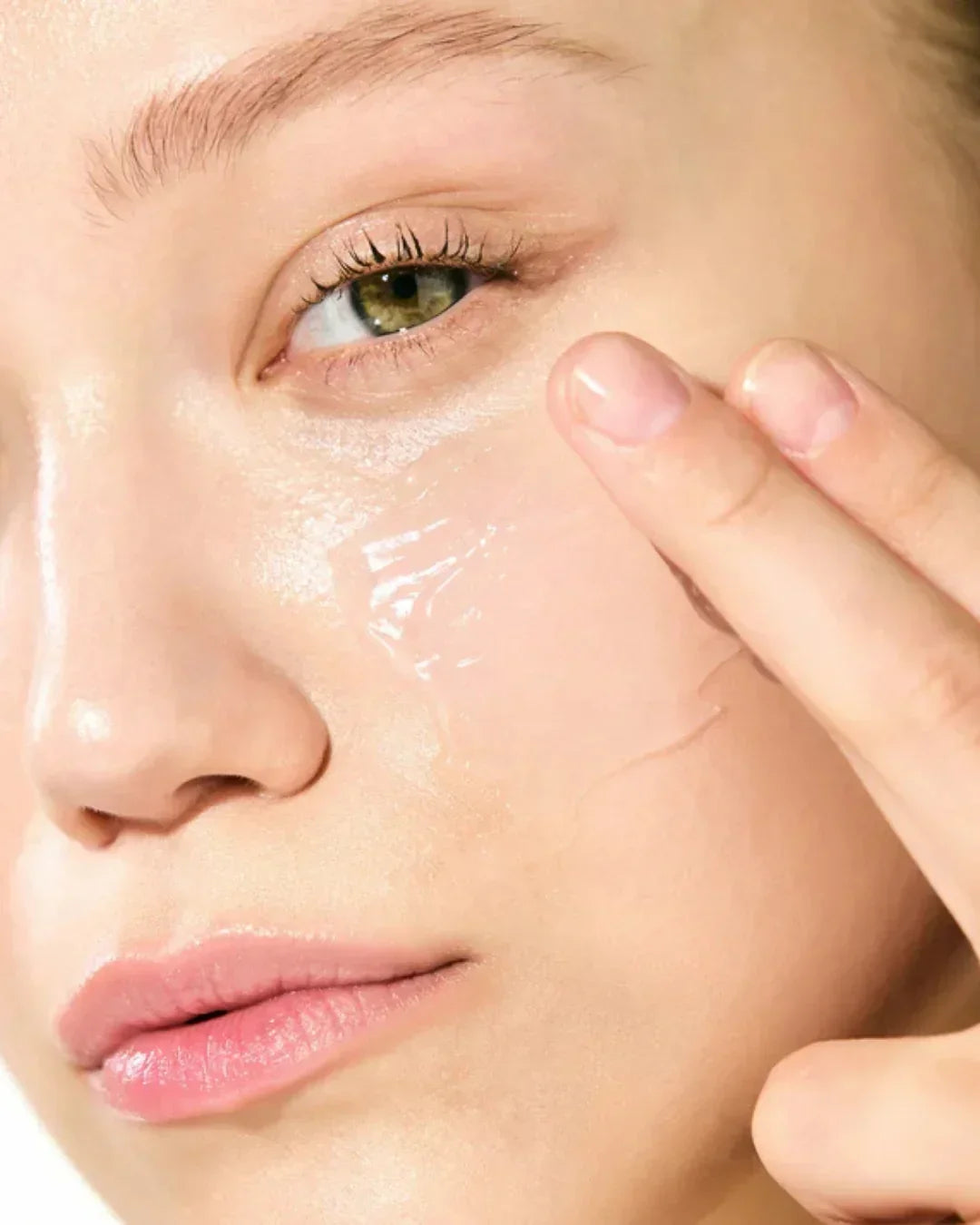 Close-up of woman applying clear moisturizing gel on her smooth face for skincare