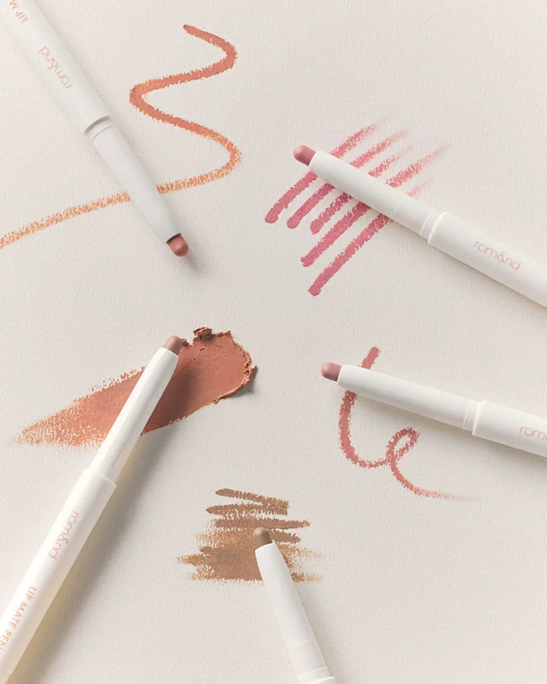 Romand Lip Mate Pencil set showing various lip pencil swatches in nude, pink, and brown shades on a textured white surface