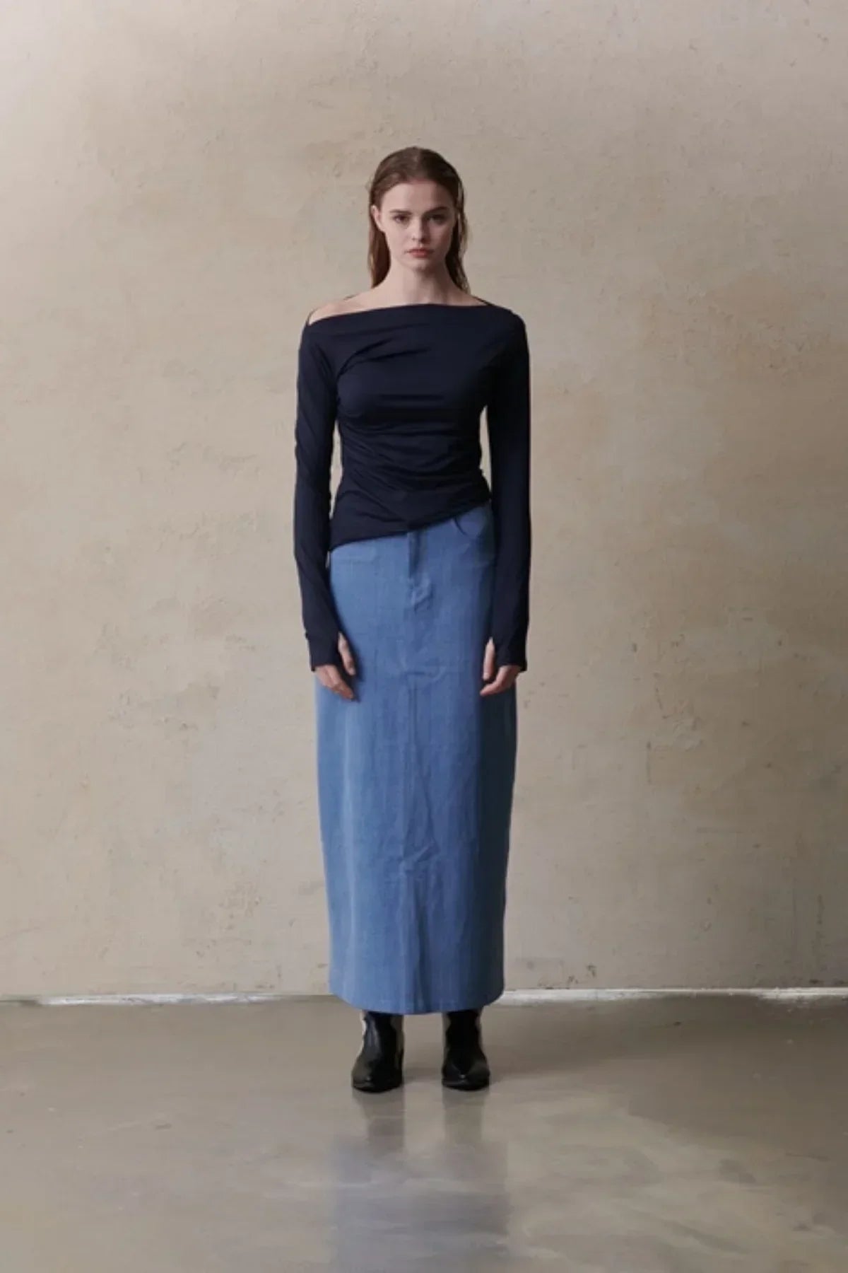 Model wearing navy off-shoulder long-sleeve top and light blue maxi skirt with black boots