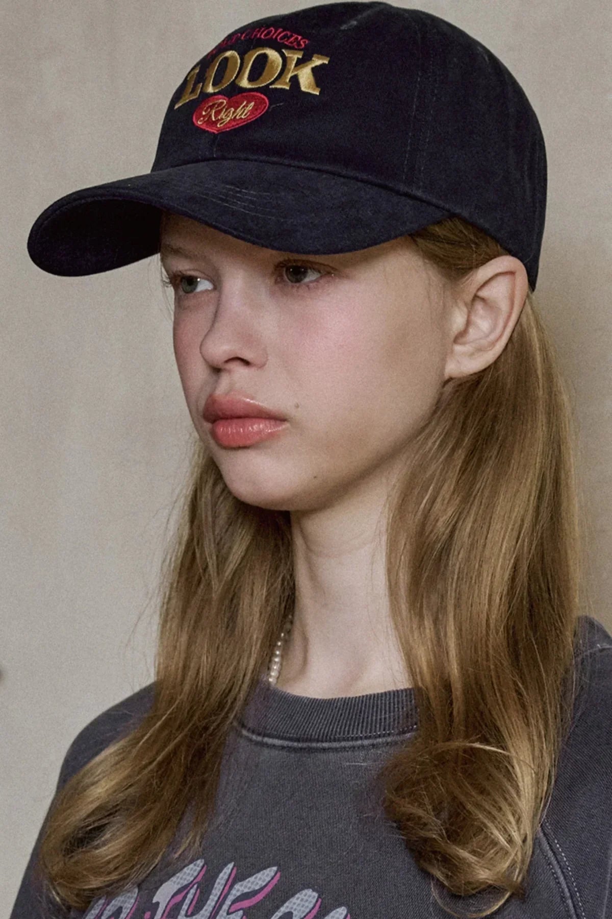 Young woman wearing navy baseball cap with Look Right embroidered logo and casual sweatshirt