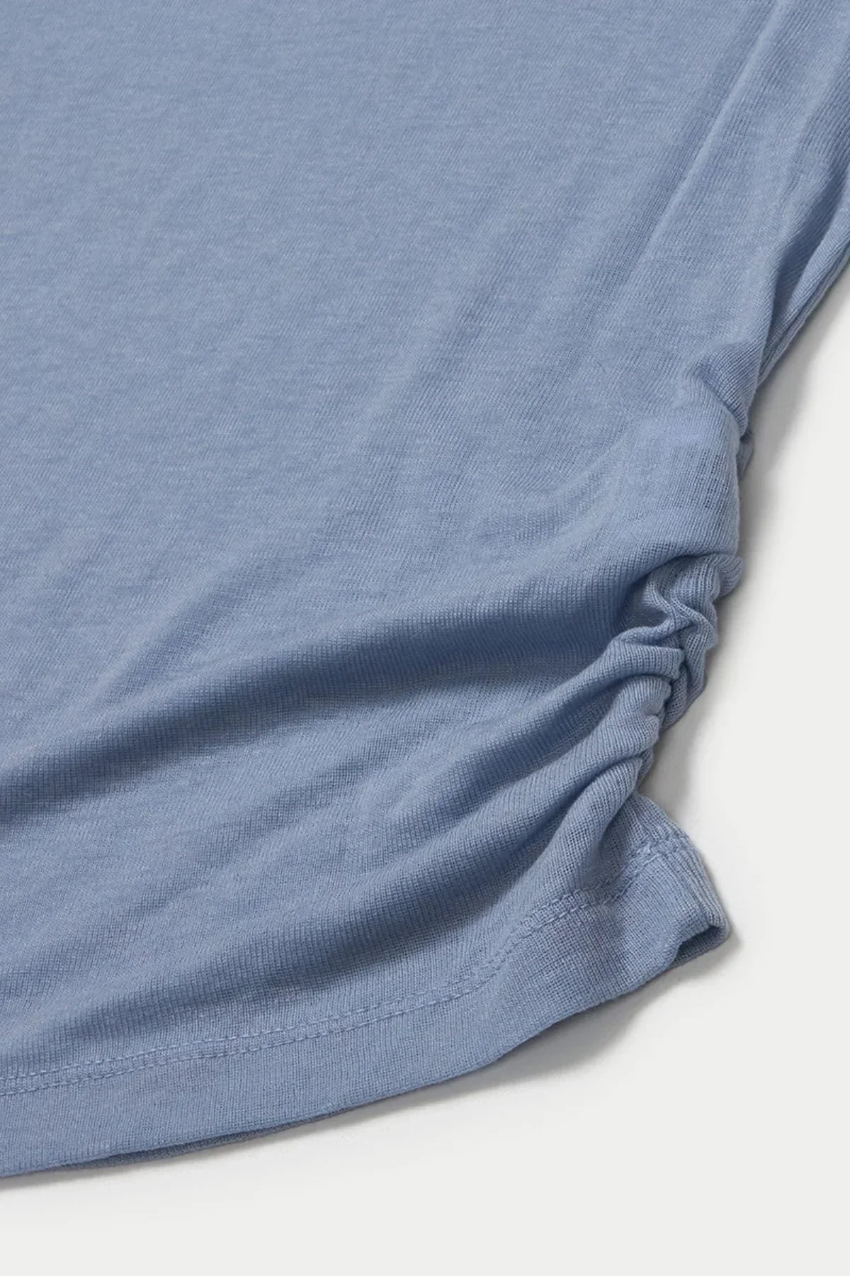 Close-up of cloudy blue loose fit long sleeve shirt fabric with gathered side detail