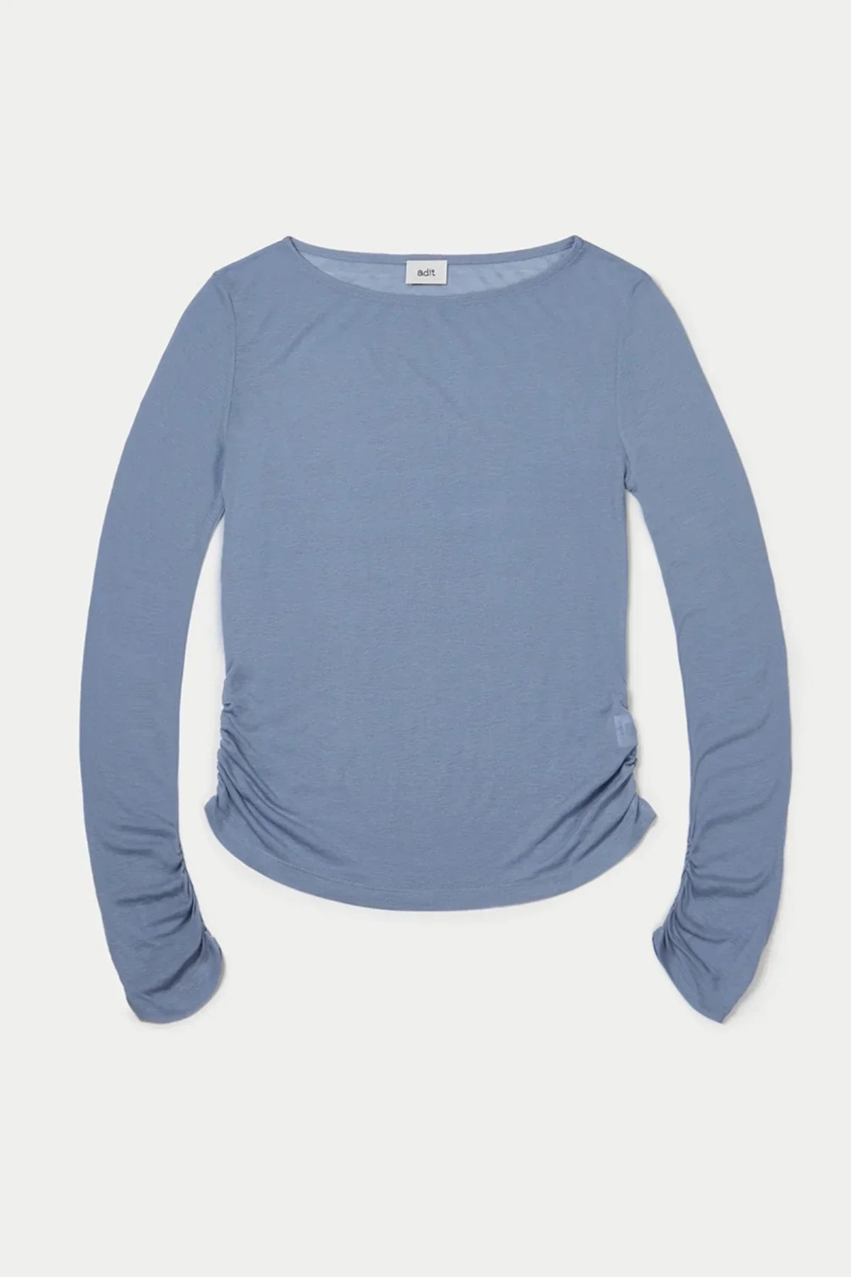 Loose fit cloudy blue long sleeve top with ruched sides laid flat on white background