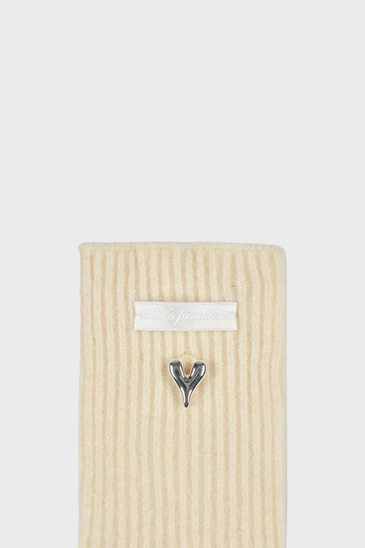 Close-up of cream ribbed knitted gloves with white label and silver heart detail