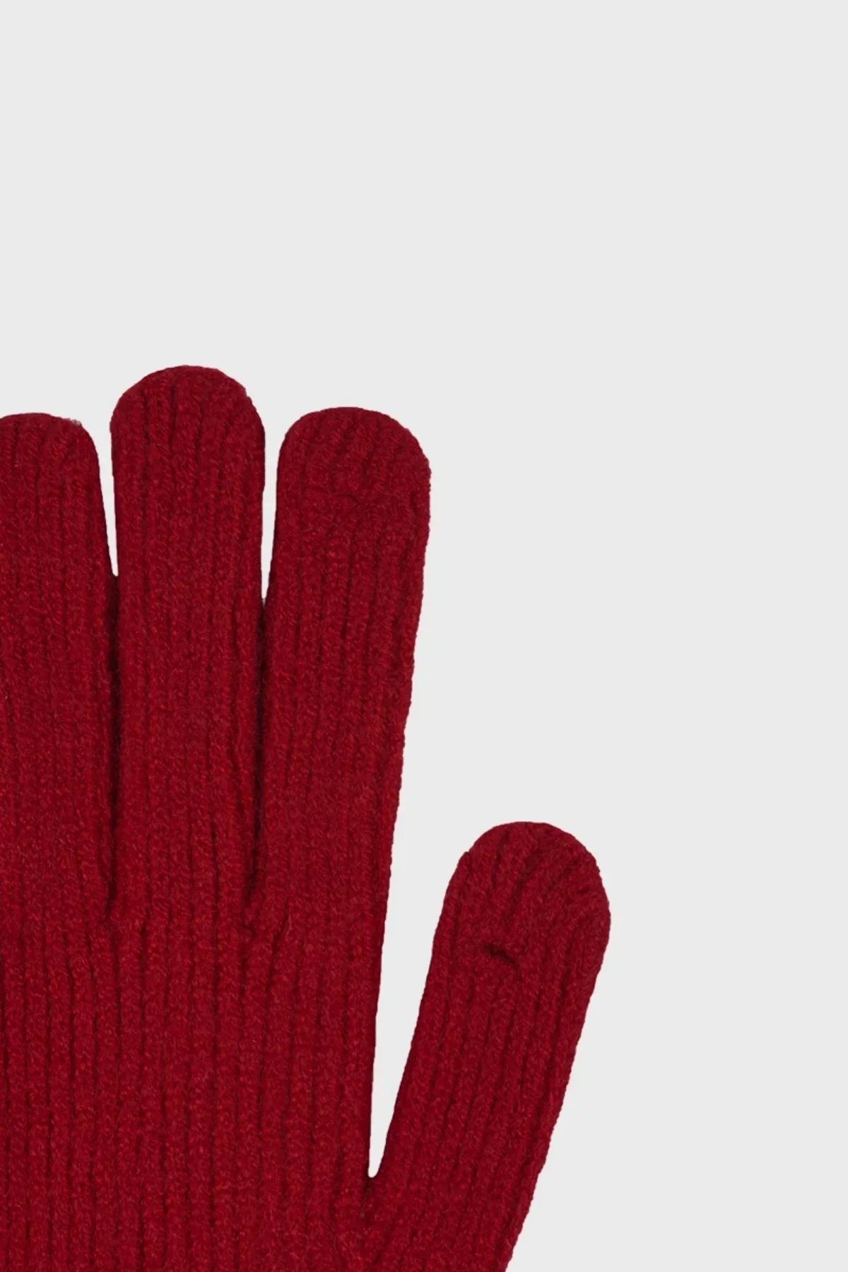 Close-up of red knitted glove fingers with ribbed texture on light background