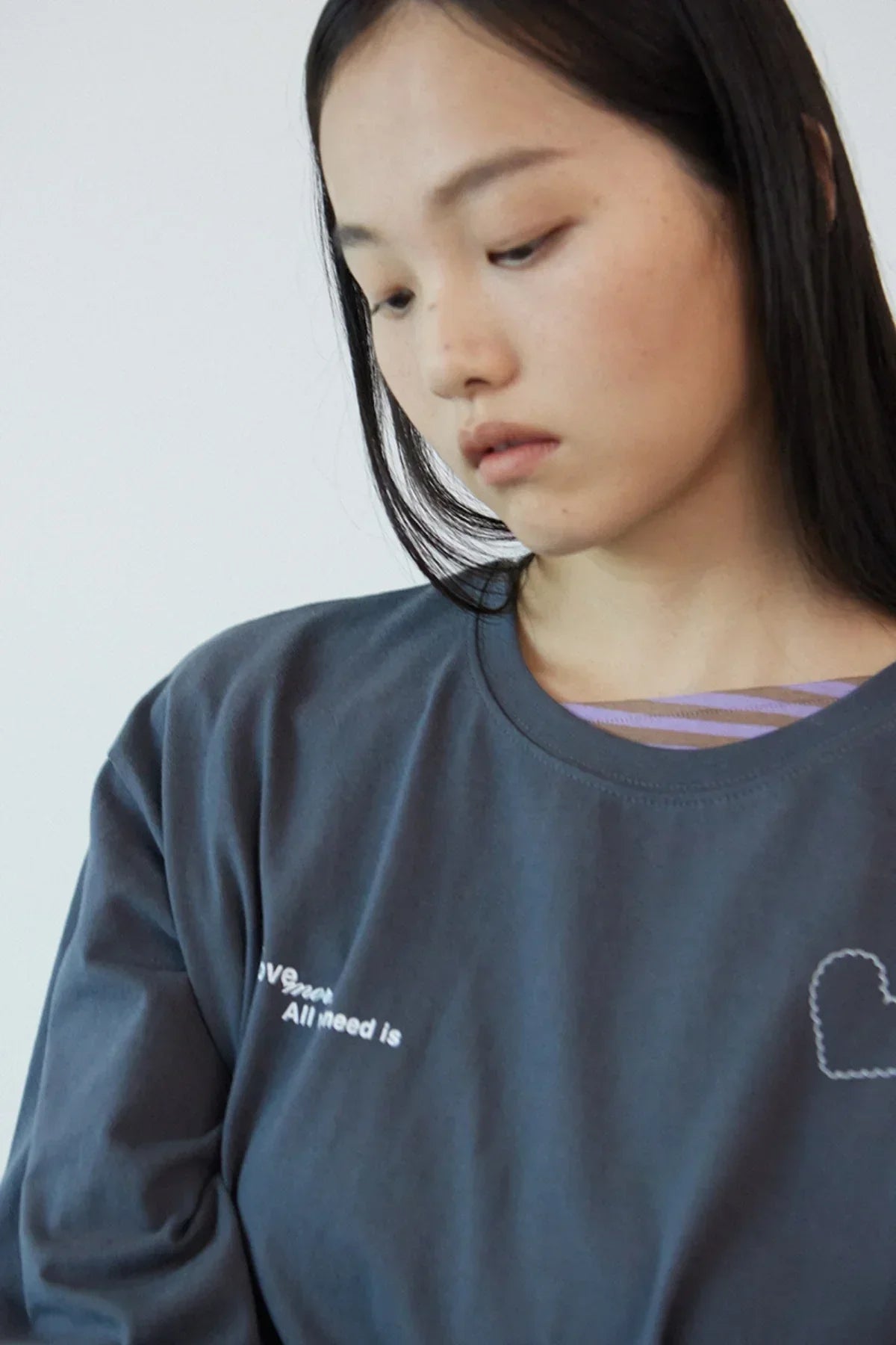 Close-up of woman wearing dark gray Love More graphic t-shirt with heart design