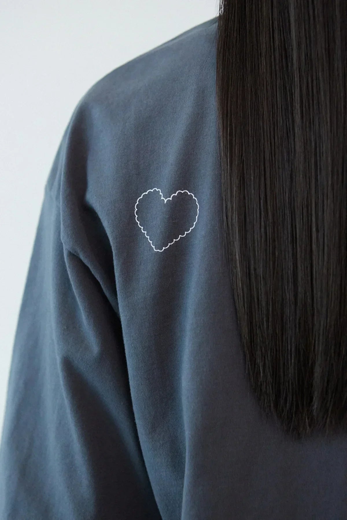 Close-up of dark gray t-shirt with small white scalloped heart design on back shoulder