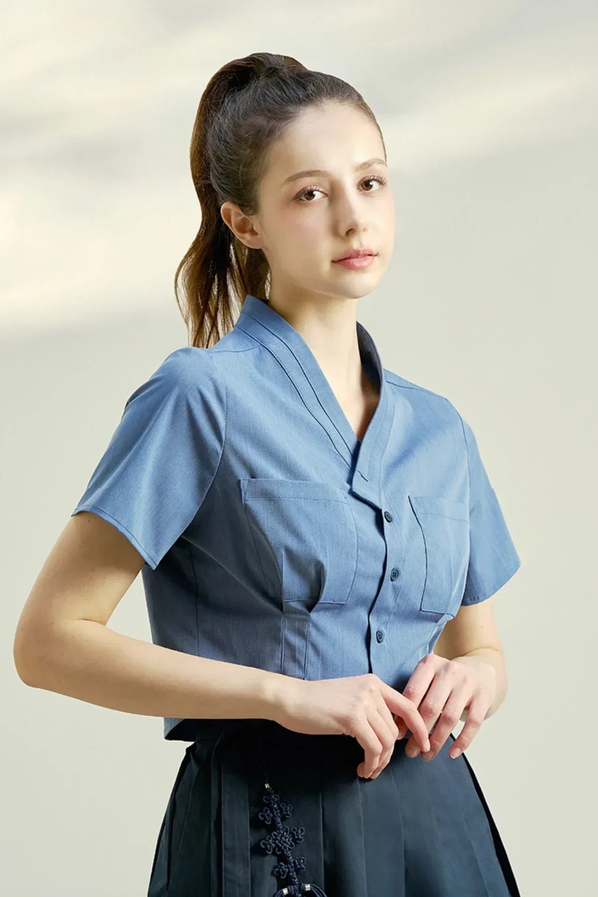 Woman wearing indigo blue short-sleeve blouse with button front and two chest pockets