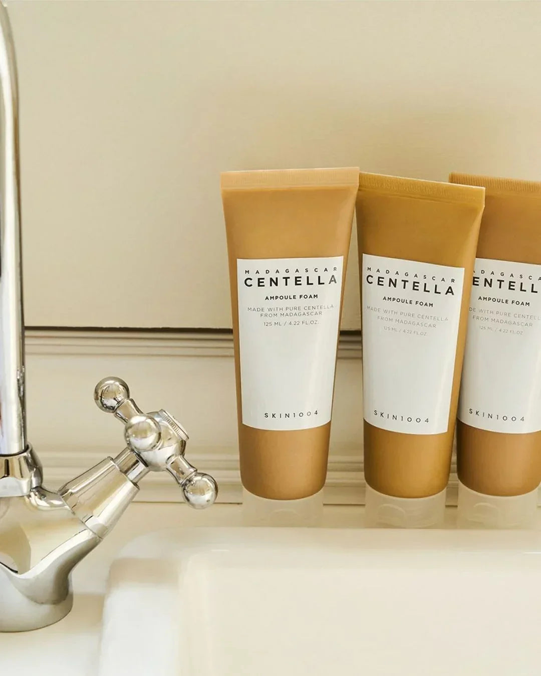 Three tubes of Madagascar Centella Ampoule Foam skincare next to a silver faucet and white sink