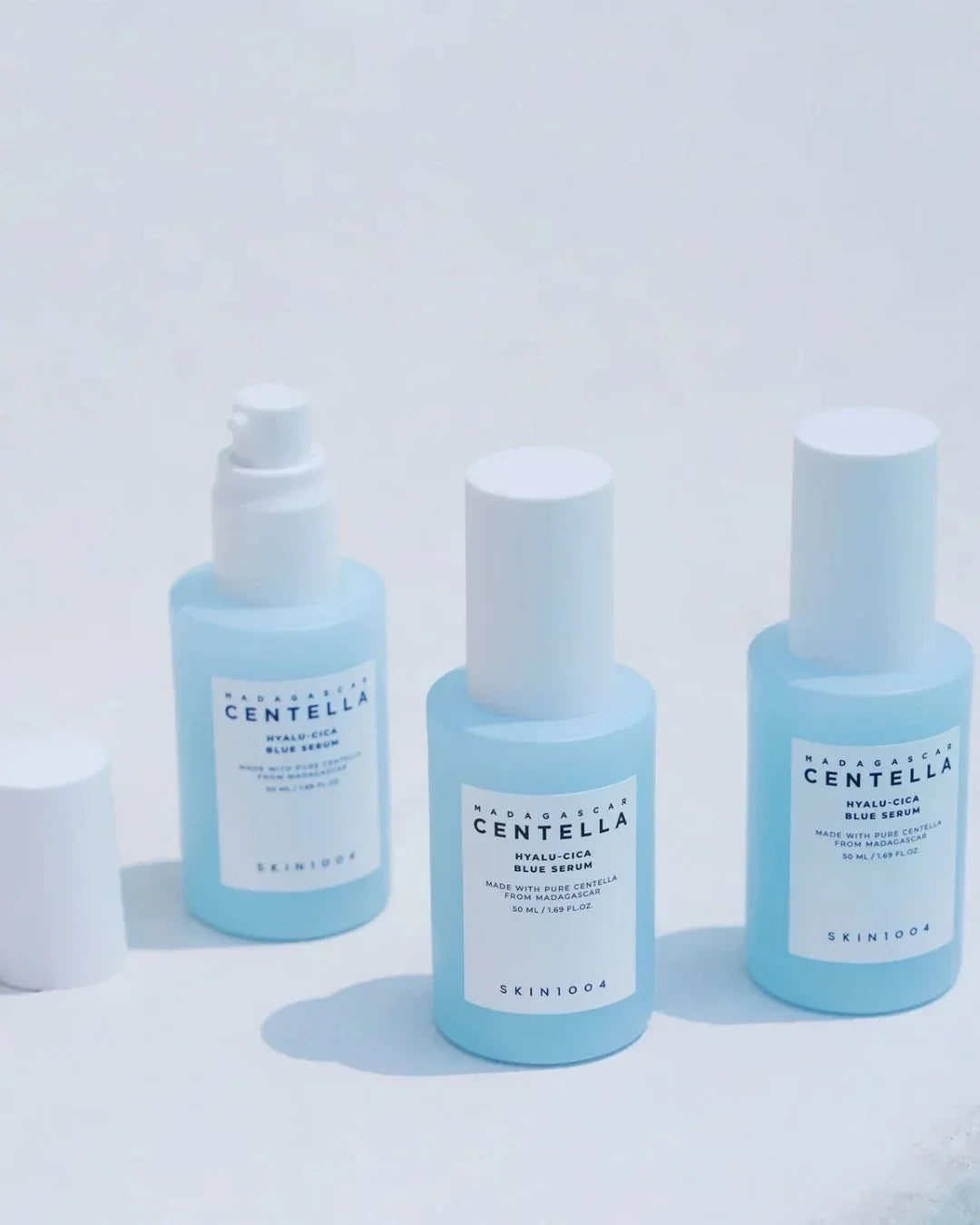 Three blue bottles of Madagascar Centella Hyalu-Cica Blue Serum by SKIN1004 on a white background