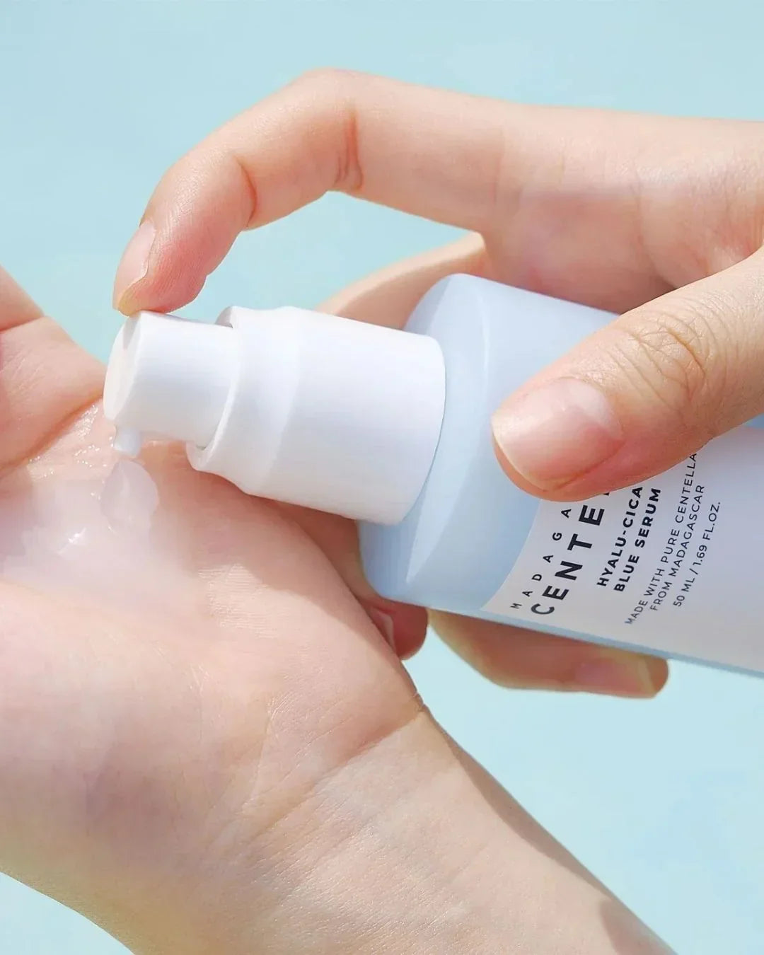 Hand dispensing Madagascar Centella Hyalu-Cica Blue Serum with clear gel texture on palm