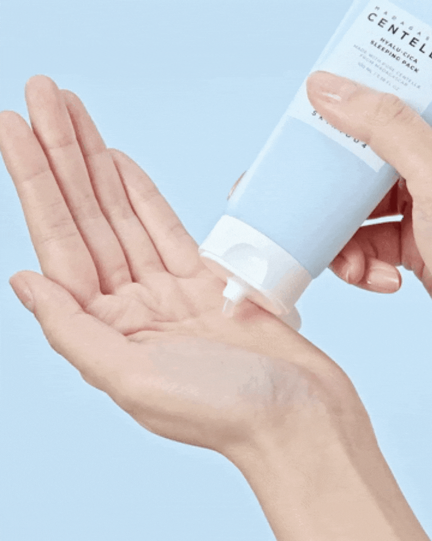 Hand squeezing Madagascar Centella Hyalu Cica Sleeping Pack cream onto palm with blue background