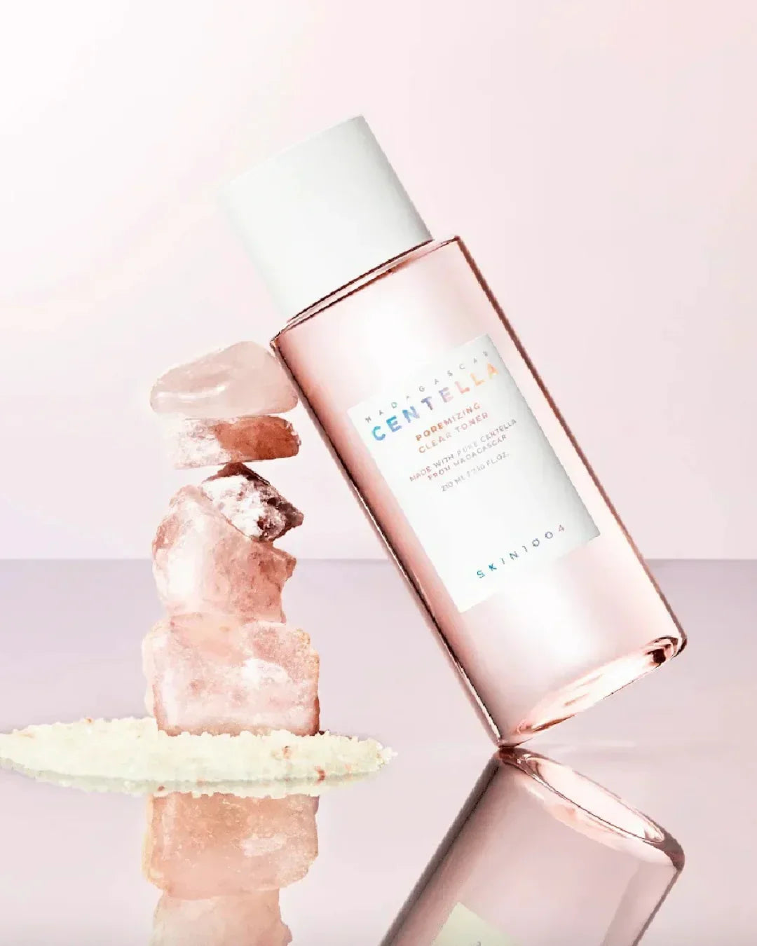 Madagascar Centella Poremizing Clear Toner bottle leaning on pink stones stack over reflective surface