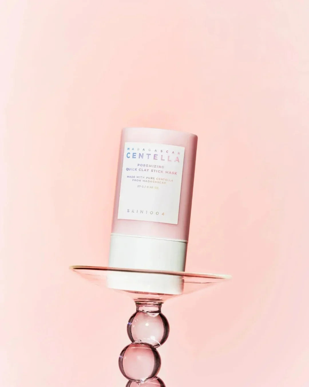 Madagascar Centella poremizing quick clay stick mask on a decorative glass stand with pink background