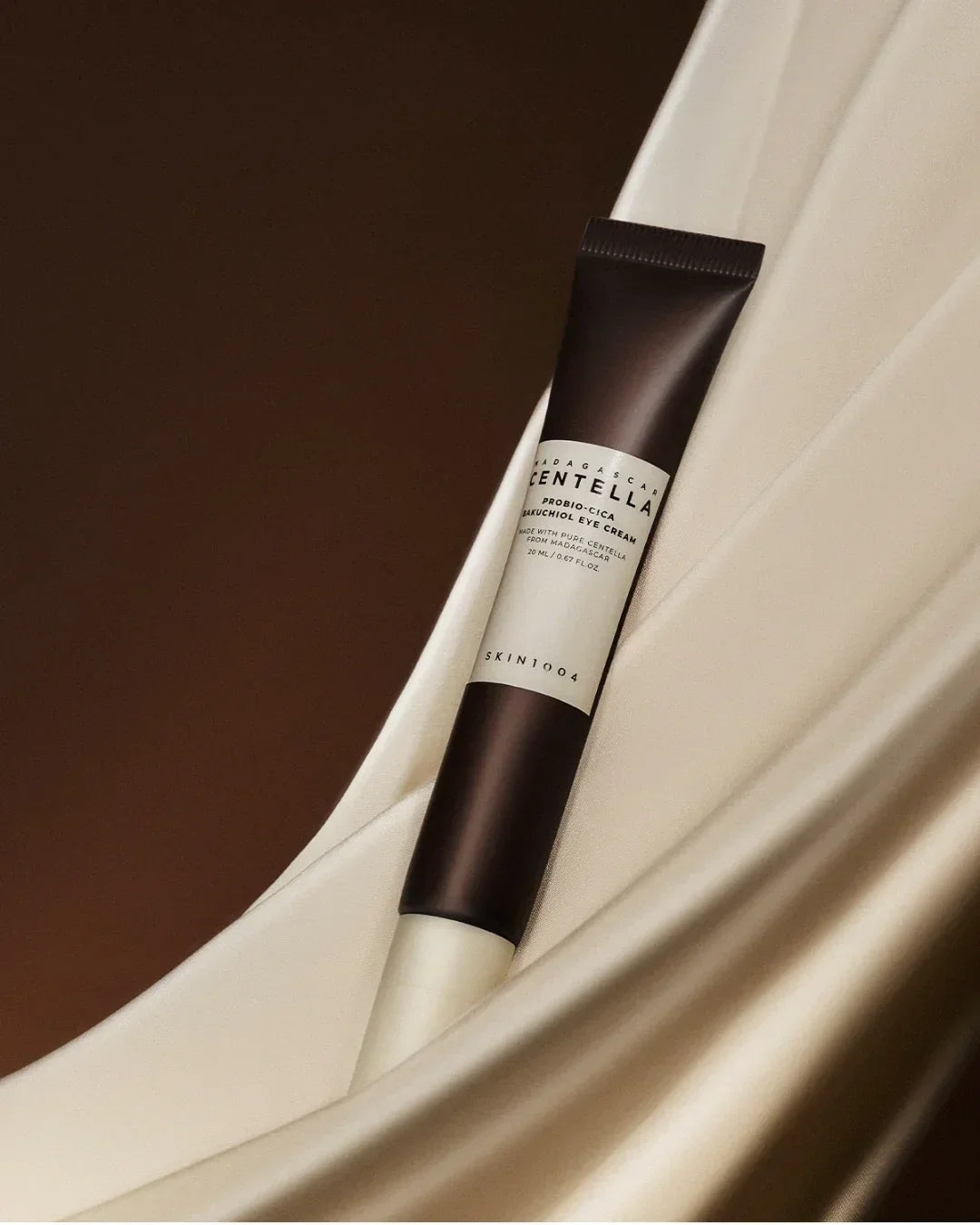Skin1004 Madagascar Centella Probio-Cica Bakuchiol Eye Cream tube on beige silky fabric