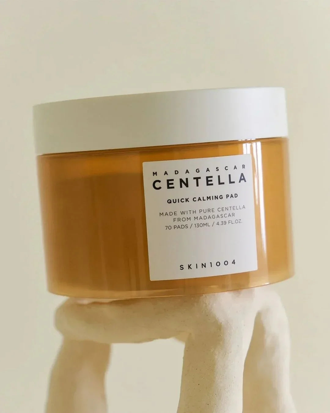 Madagascar Centella Quick Calming Pad skincare product in amber jar with white lid on beige stand