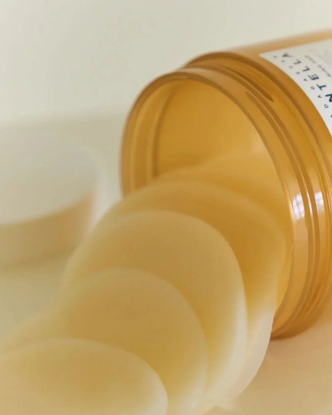 Amber jar spilling round Madagascar Centella calming pads on white surface