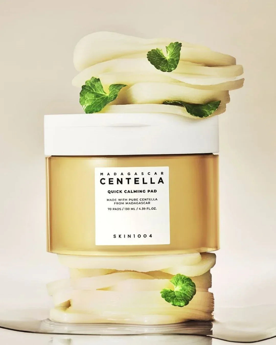 Skin1004 Madagascar Centella Quick Calming Pad jar with fresh green centella leaves and cream swirls