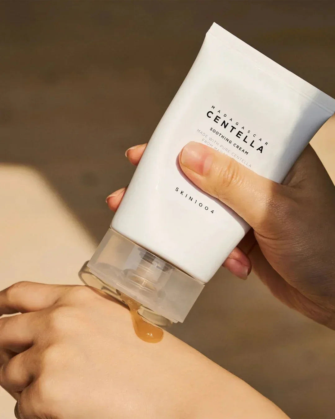 Hand dispensing Madagascar Centella Soothing Cream gel on back of other hand in soft natural light