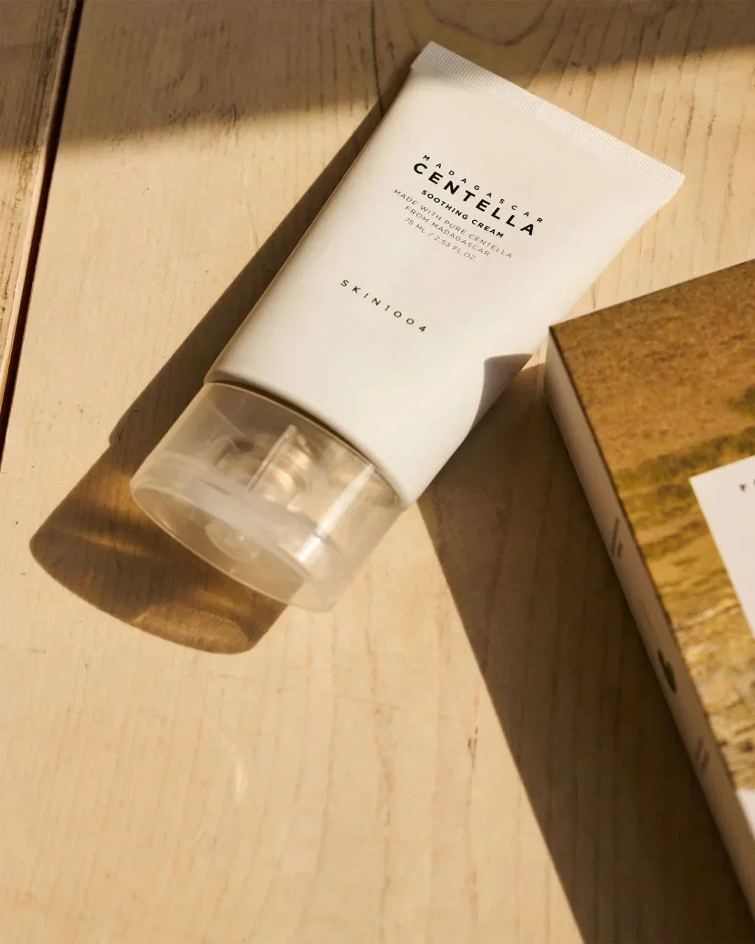 Tube of Madagascar Centella Soothing Cream by Skin1004 on wooden surface in natural light