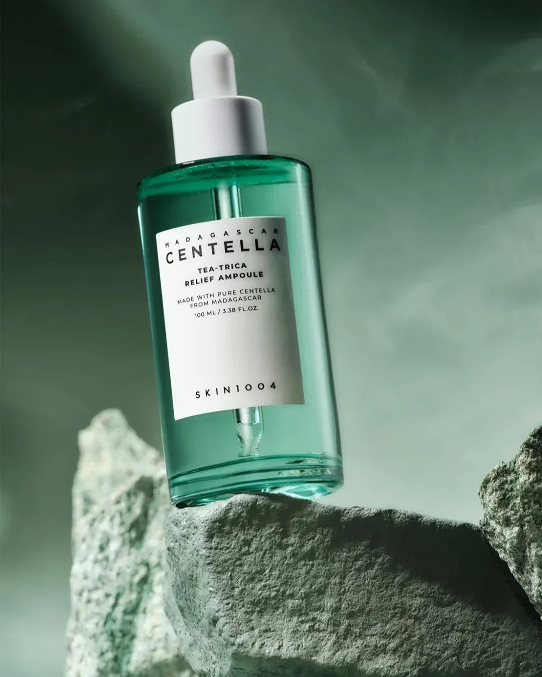 Madagascar Centella Tea-Trica Relief Ampoule skincare bottle on textured green rocks with soft green background