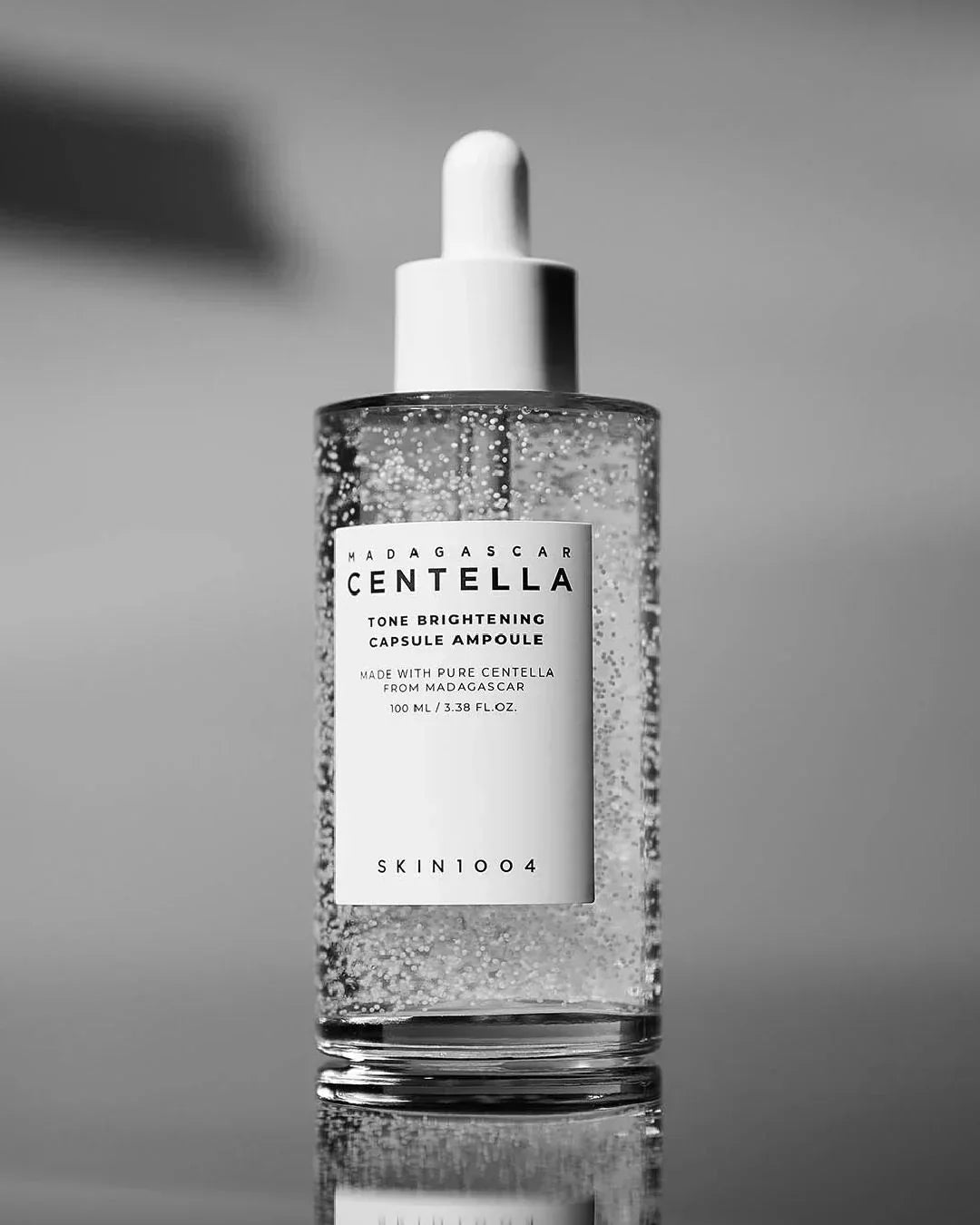 Madagascar Centella tone brightening capsule ampoule serum bottle with dropper on gray background