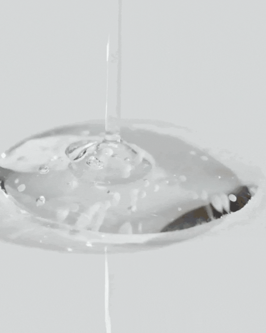 Clear gel serum dripping onto a spoon, showcasing smooth texture and bubbles