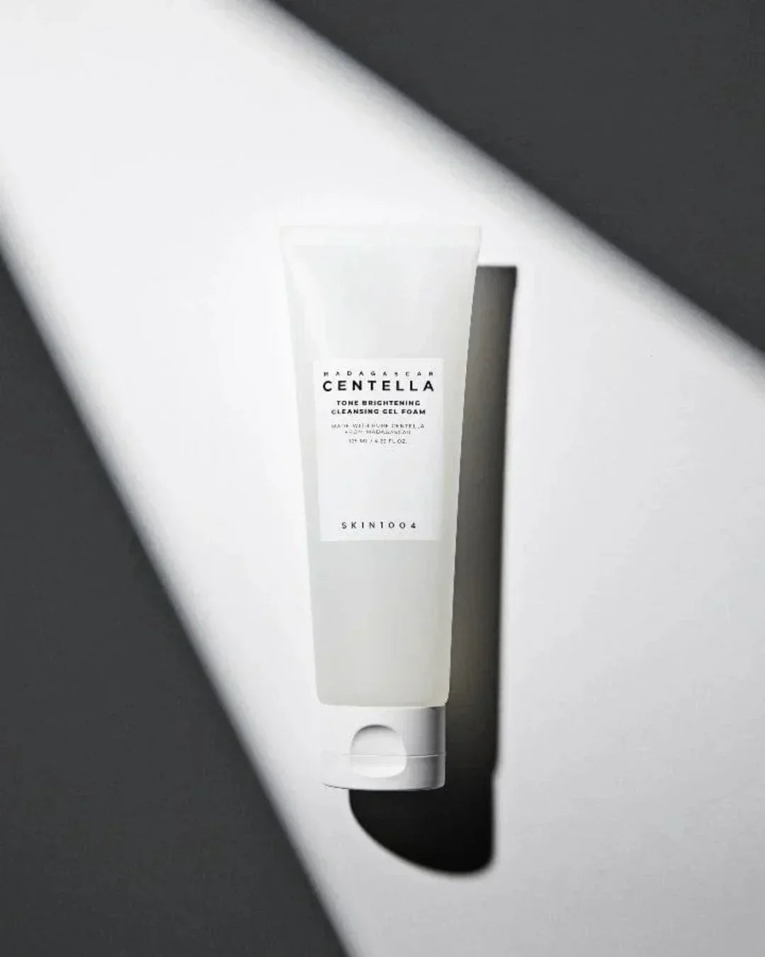 Madagascar Centella tone brightening cleansing gel foam in a white squeeze tube on light and shadow background